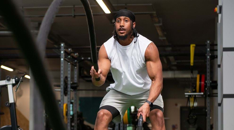 Man using battle ropes in gym setting